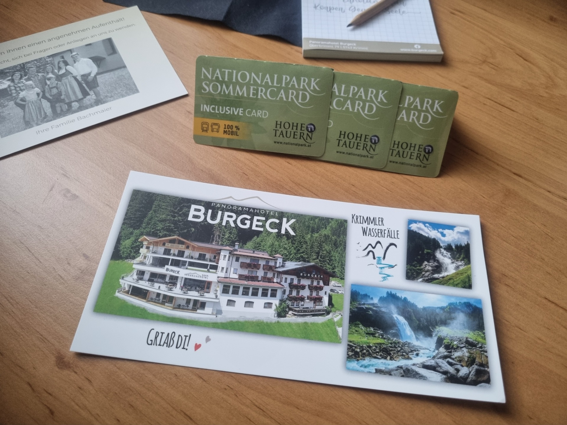 Zelené Nationalpark Sommercard karty a brožury na dřevěném stole, vedle tužka a kniha.